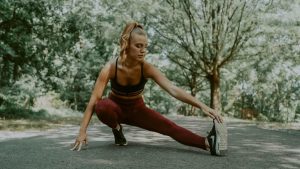 Full length of focused female athlete doing lunges forward while stretching legs in park